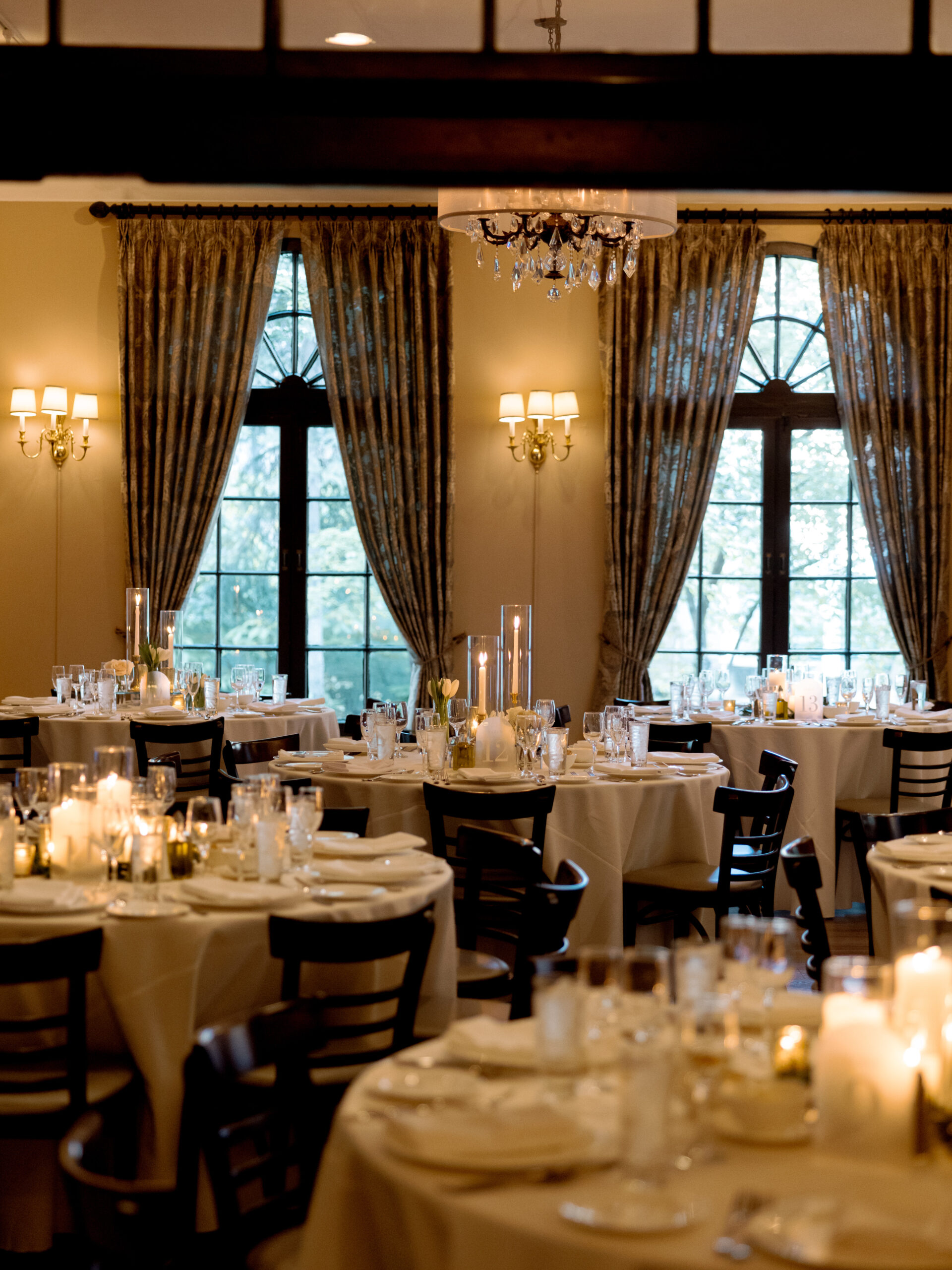 Jena and Andrew's wedding dinner tables beneath tall draped windows at Loft and Garden