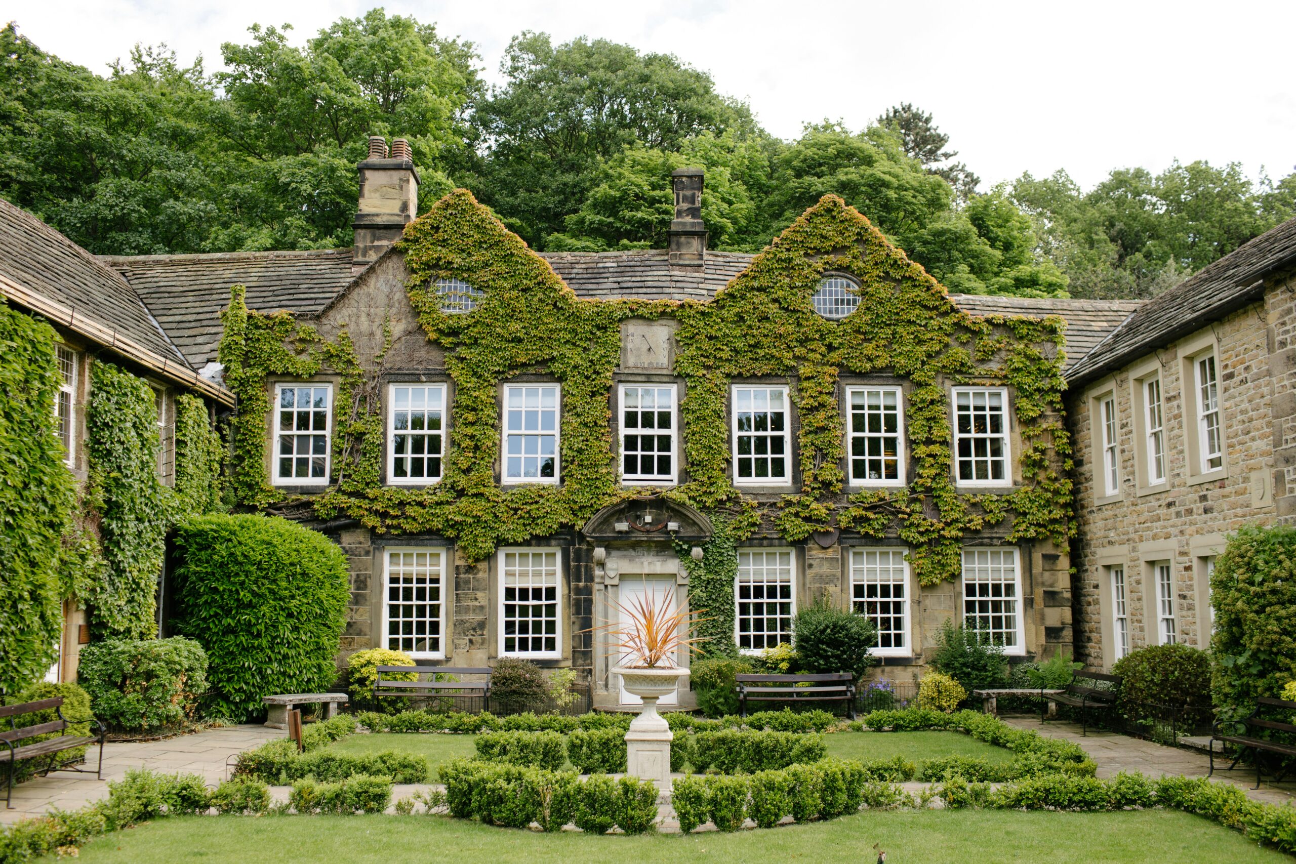 Ivy-covered stone building at Loft & Garden framed by clipped hedges and a formal lawn