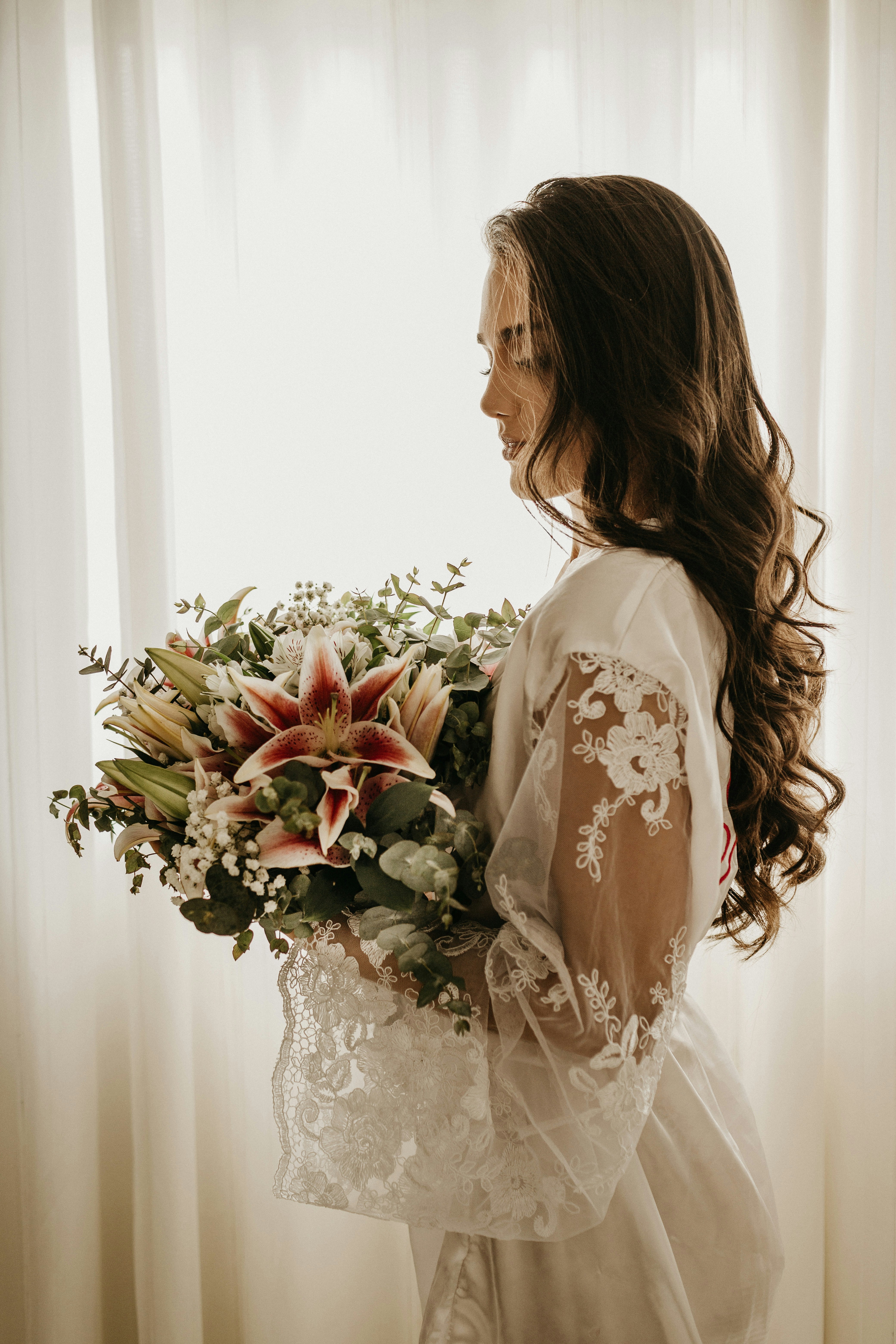 Bride in a laced-back ball gown standing among tall pines