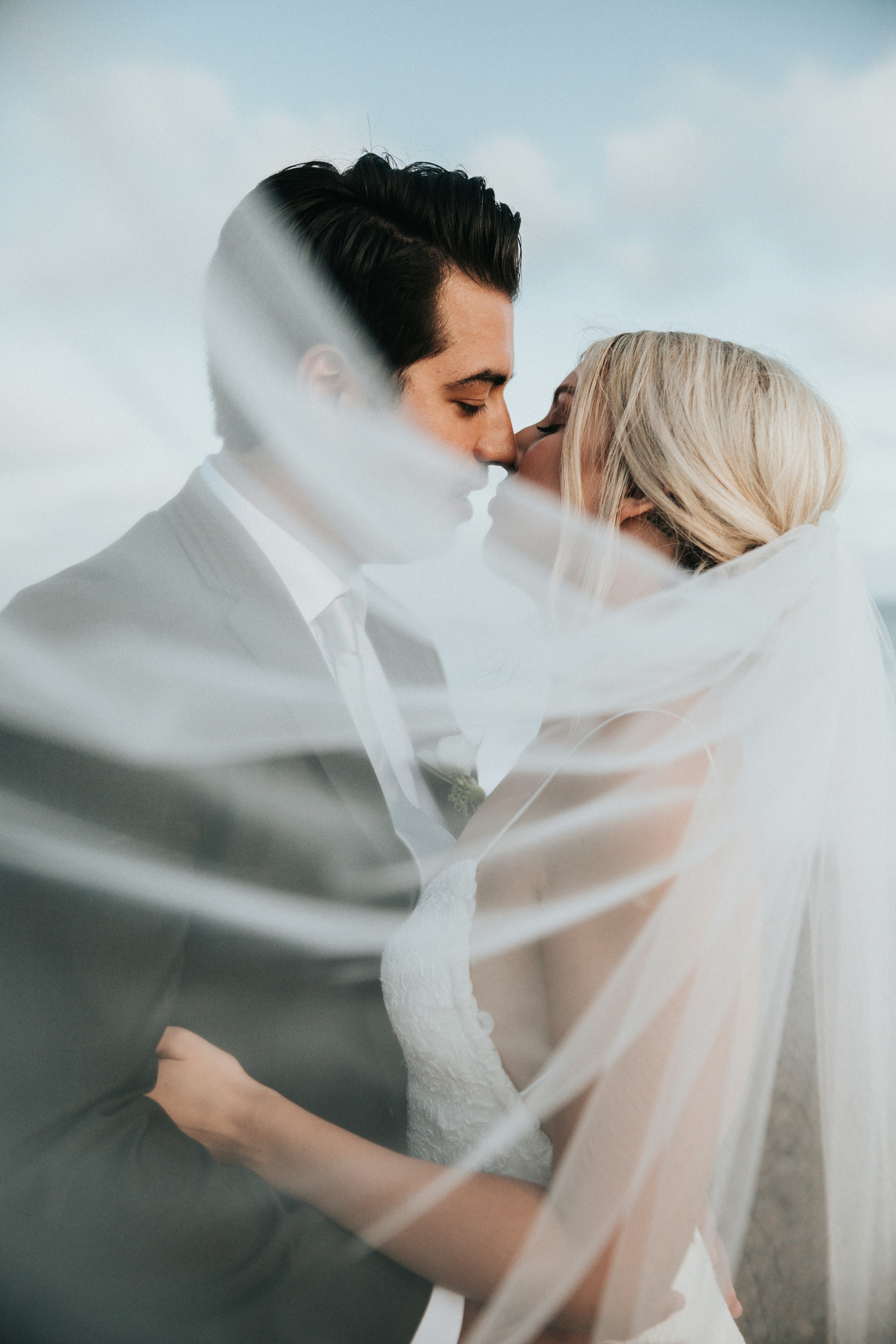 Bride in a lace-sleeved gown smiling over a bouquet of pampas grass and pale roses